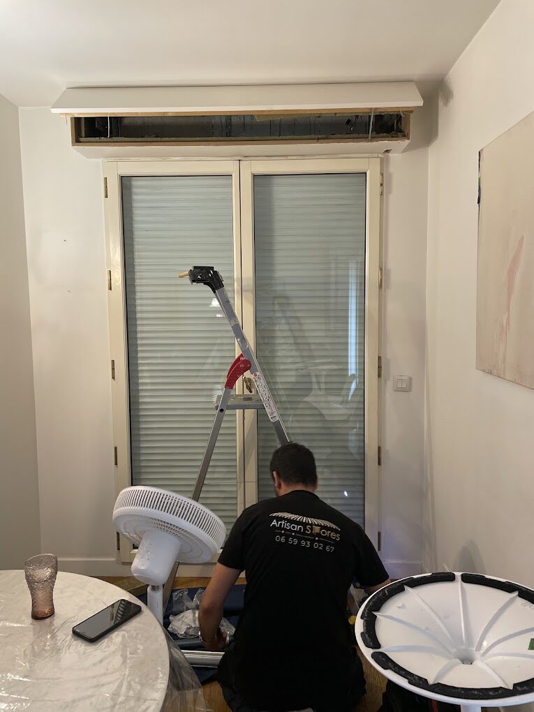 Technicien de l'entreprise en intervention sur une porte-fenêtre équipée de volets roulants
